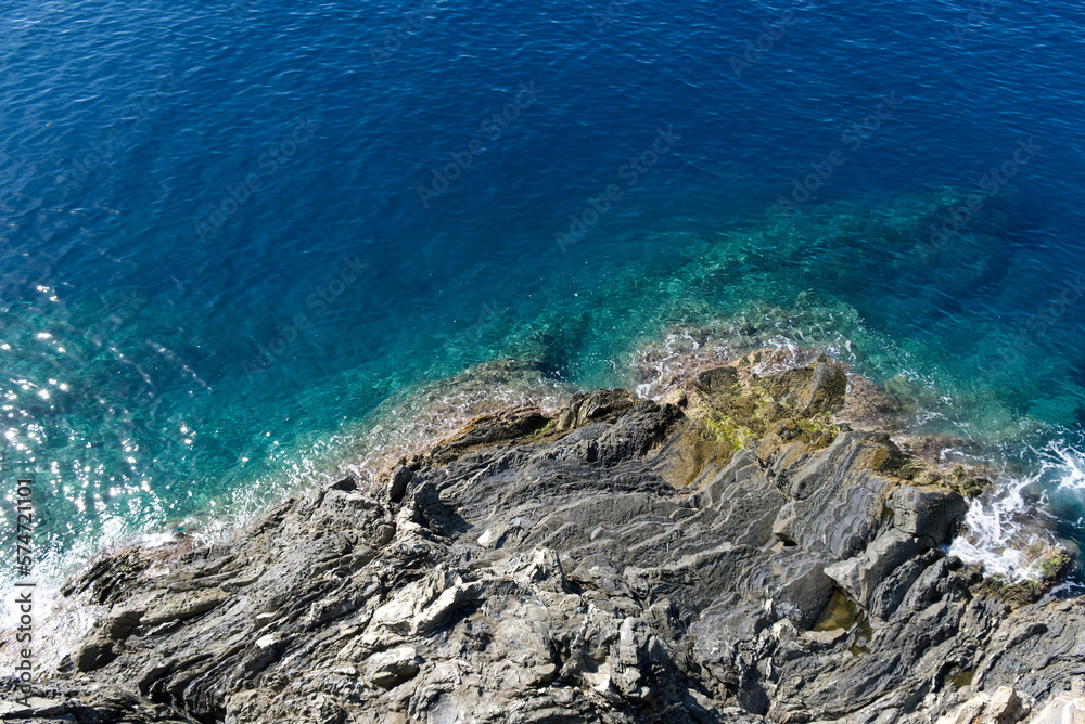Top view of a turquoise sea and black granite cliff