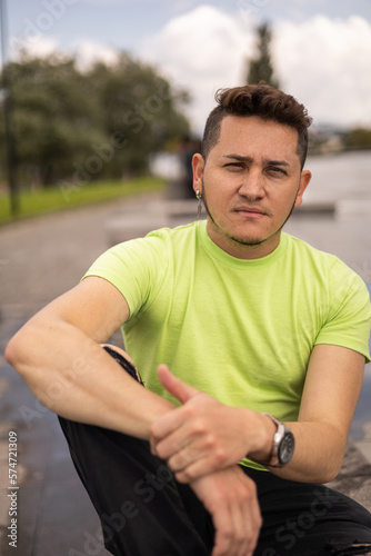 young man with short hair and wearing casual clothes with t-shirt, sitting resting in the city, male model lifestyle and fashion