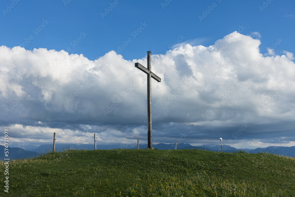 Summit of the mountain Hirschberg with summit cross in front of huge clouds