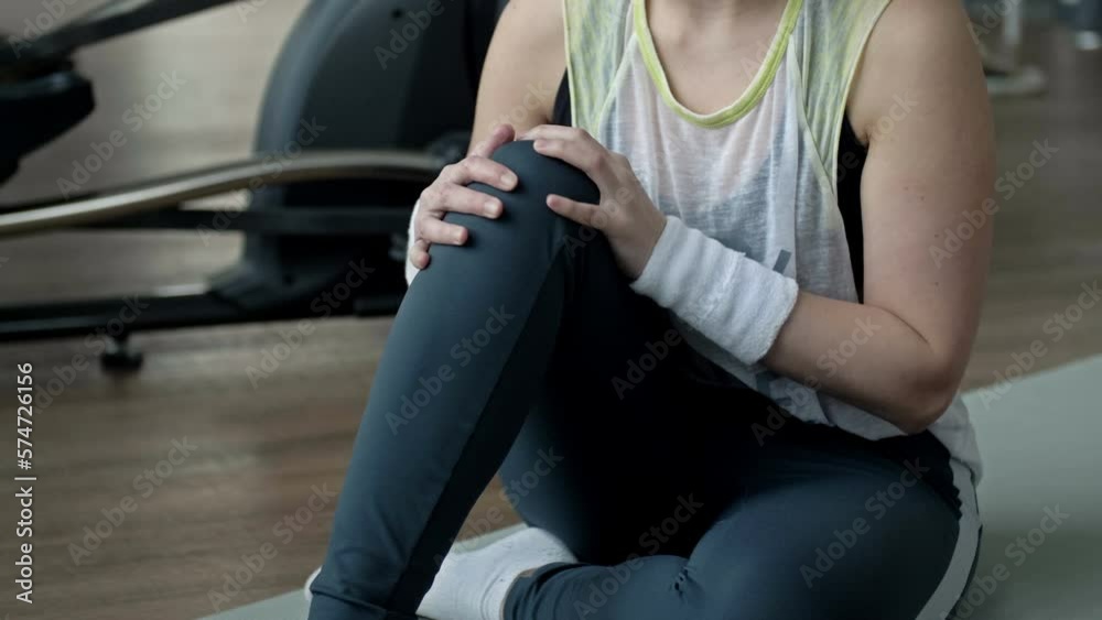 Young woman feel pain from knee muscle injury while exercising in fitness room.