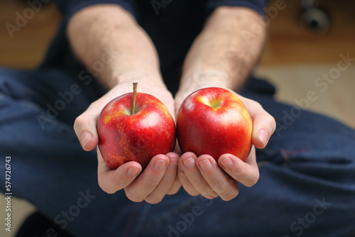a person holding two red apples