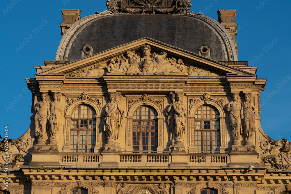 Paris, France - 02 21 2023: Details of facade of the Louvre museum and Louvre pyramid from the Napoleon courtyard