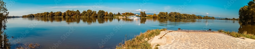 High resolution stitched autumn panorama with reflections and a ferry near Stephansposching, Danube, Bavaria, Germany