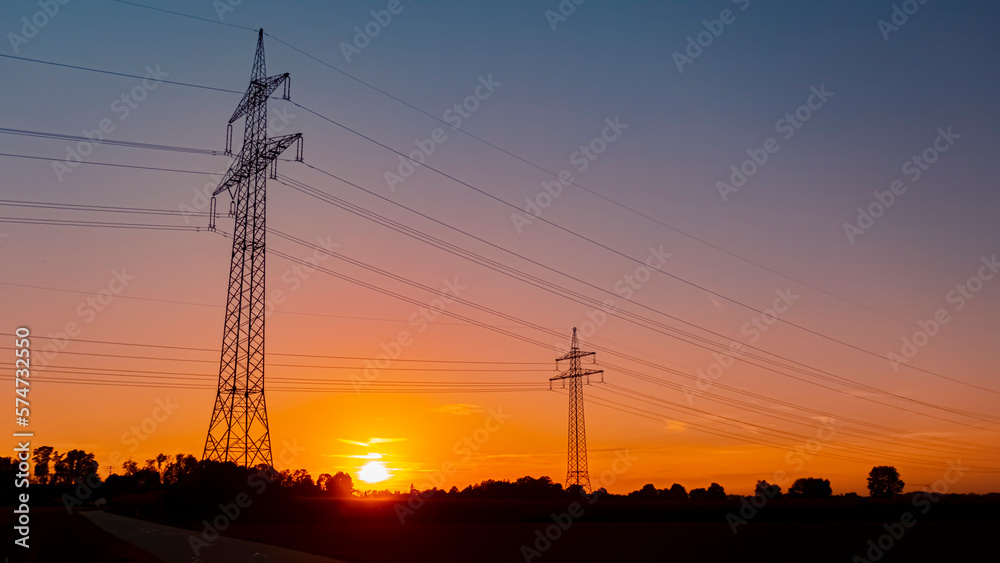 Beautiful sunset with a dramatic sky and overland high voltage lines near Tabertshausen, Bavaria, Germany