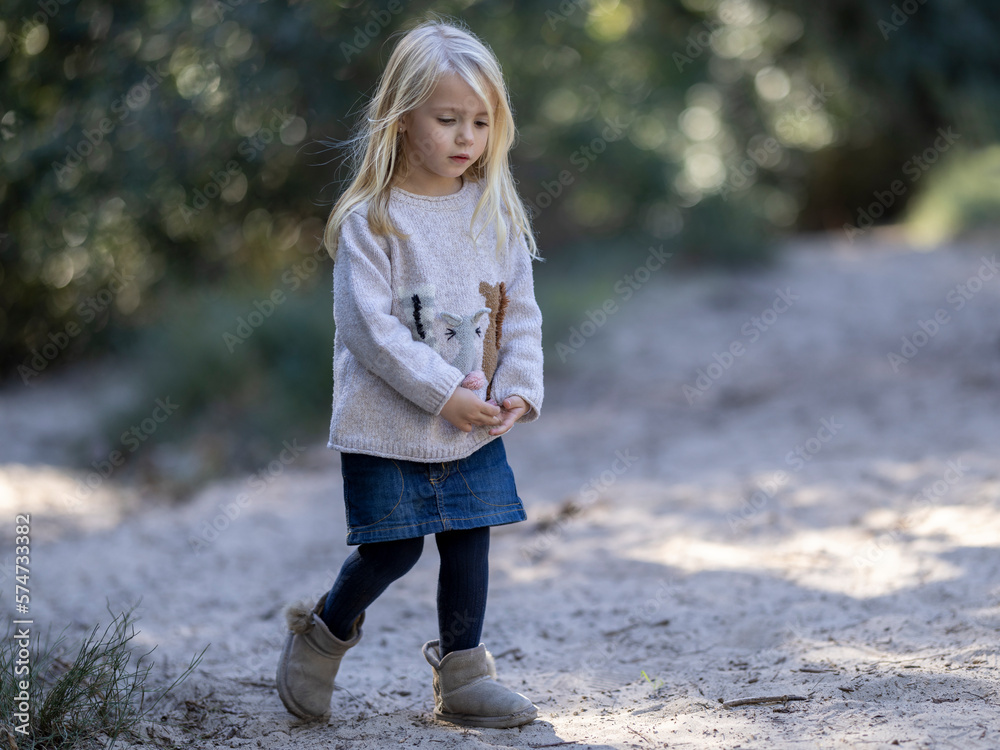 Little girl walking thoughtfully in the woods