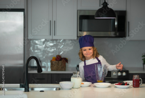 Chef child cooking. Little chef preparing healthy meal. Cute kid boy in chef uniform on kitchen.