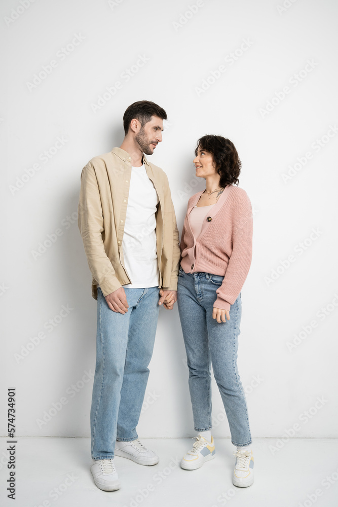 Full length of smiling couple holding hands while standing on white background. Full length of smiling couple holding hands while standing on white background.