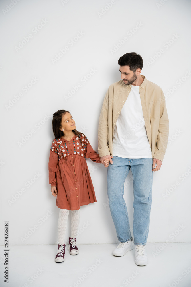 Smiling man holding hand of preteen daughter on white background. Smiling man holding hand of preteen daughter on white background.