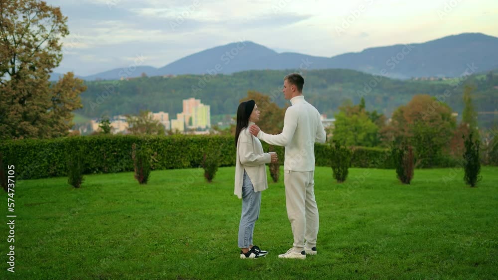 Young couple in white clothes stay mountains background, hug each other and talk Young couple in white clothes stay mountains background, hug each other and talk