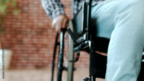 Close-up view from below a guy, disabled person with a lesion of the spinal cord and legs, multiple sclerosis, in a wheelchair enters the frame, home environment, indoor