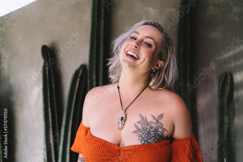 Happy woman with tattoo on body standing in cafe