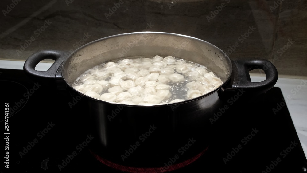 Small size meat dumplings are boiling in a pot on the stove. Pelmeni are the traditional national Russian cuisine. Italian ravioli. Food for children. Dish for kid. Cooking lunch or dinner for family Small size meat dumplings are boiling in a pot on the stove. Pelmeni are the traditional national Russian cuisine. Italian ravioli. Food for children. Dish for kid. Cooking lunch or dinner for family