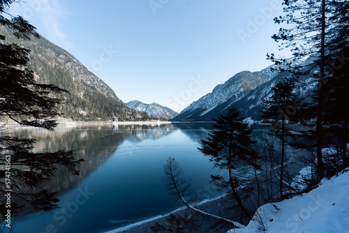 Fototapeta Naklejka Na Ścianę i Meble -  the beautiful lake plansee photographed in the day with the mountains covered with snow and the lake plansee in the foreground with crystal clear water