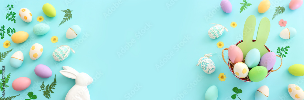 Cute bunny next to easter colorful eggs over blue pastel background