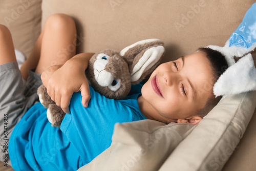 Canvas Print Happy brazilian child with bunny ears hugging easter plush rabbit lying in the s