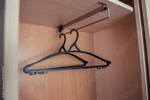 Two empty black clothes hangers hanging in wooden wardrobe in sale season. Fashion business and marketing concept.