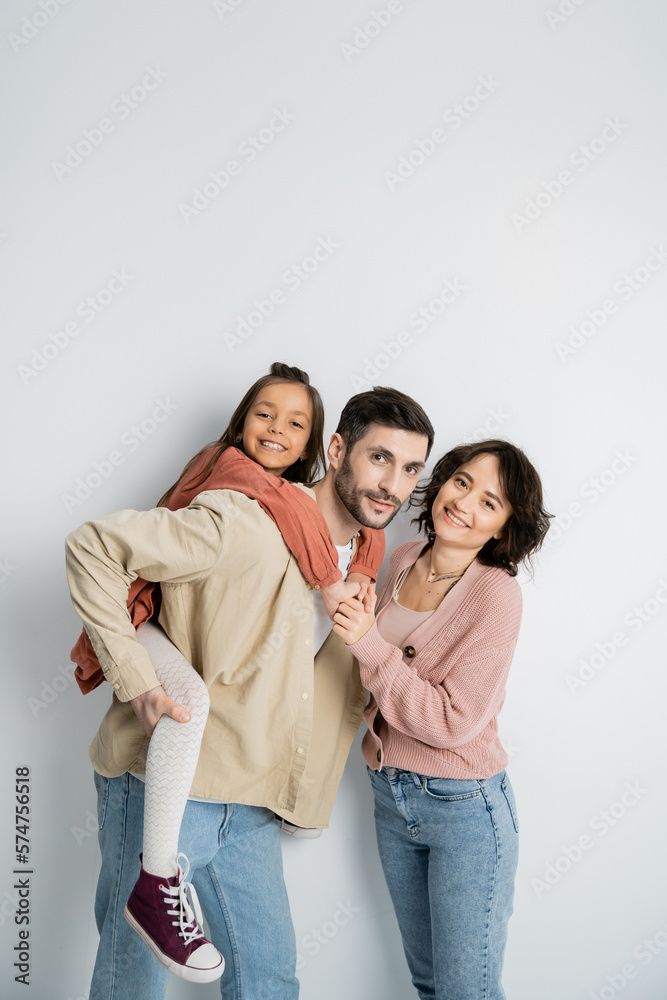 Cheerful girl piggyback on dad near mom on white background. Cheerful girl piggyback on dad near mom on white background.