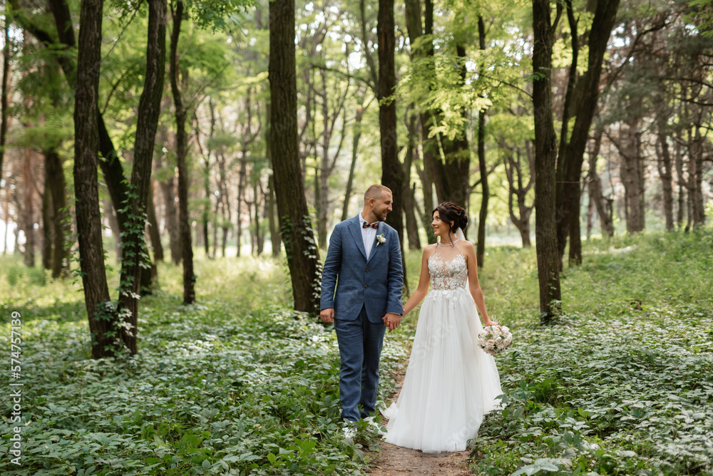 wedding walk of the bride and groom in the deciduous forest in summer wedding walk of the bride and groom in the deciduous forest in summer