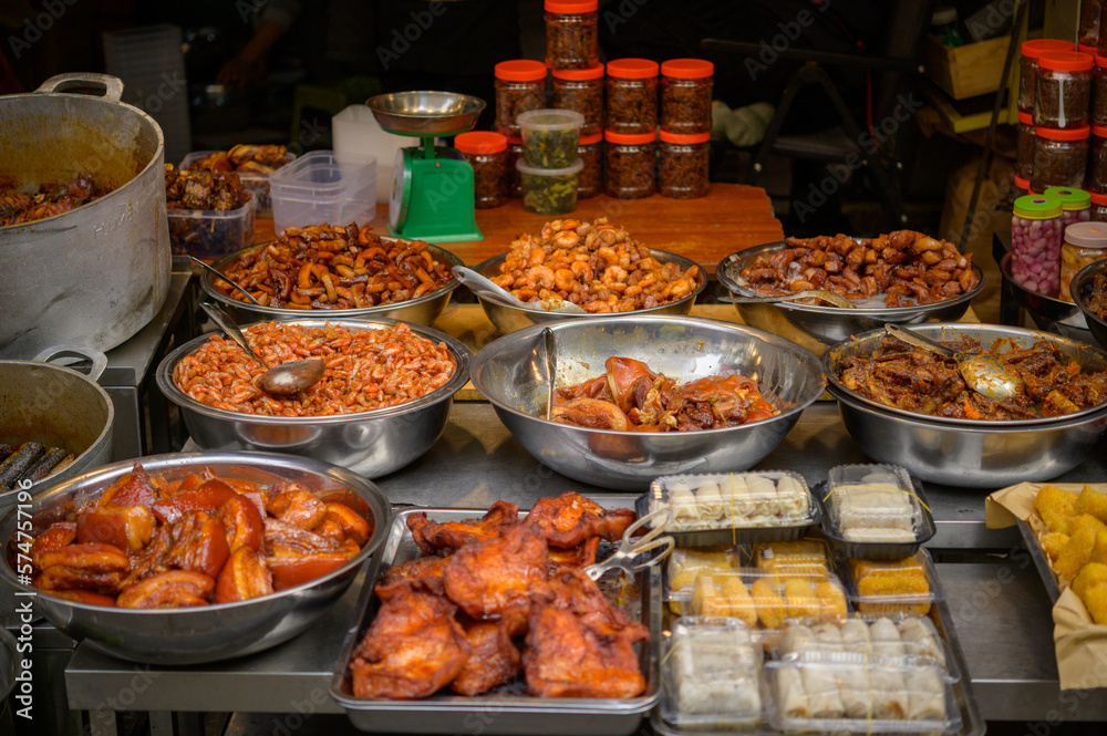 High angle pieces of smoked pork in various metal and plastic containers placed on stall in local bazaar of Vietnam