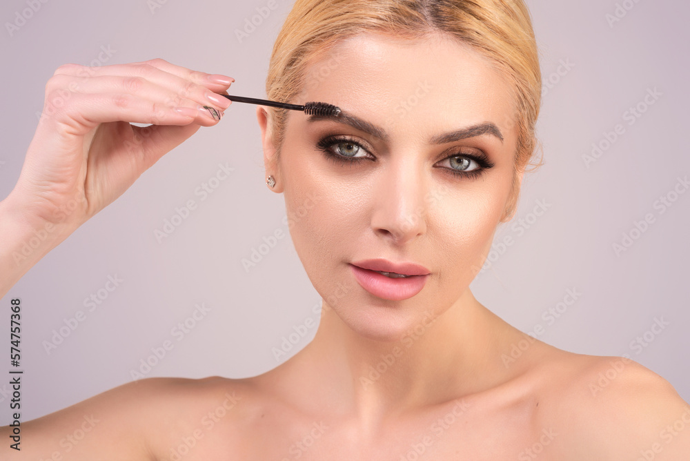 Eyebrow shaping, woman combs eyebrows with a brus. Eyebrow line. Makeup and cosmetology concept. Female model with long eyelashes and thick eyebrows. Perfect shaped brow.
