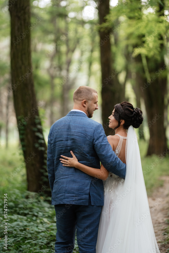 wedding walk of the bride and groom in the deciduous forest in summer wedding walk of the bride and groom in the deciduous forest in summer