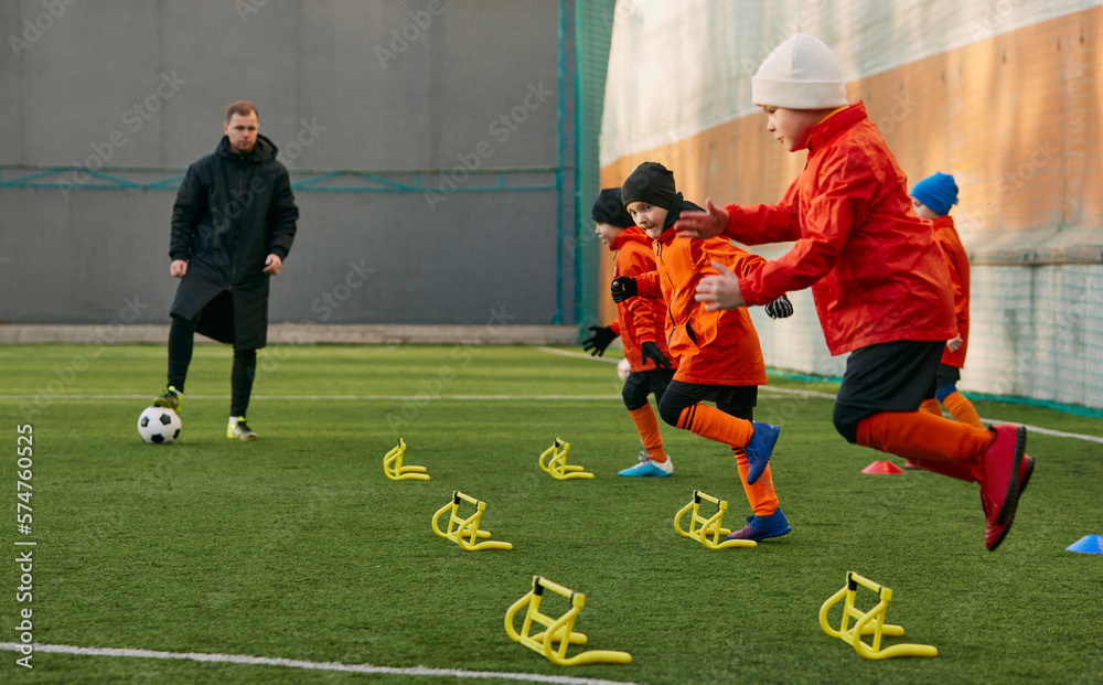 Fast movements. Boys, children, football players doing exercises, warming up before training session with coach on sports field outdoors. Sport, childhood, active lifestyle, hobby, sport club concept
