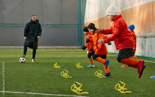 Fast movements. Boys, children, football players doing exercises, warming up before training session with coach on sports field outdoors. Sport, childhood, active lifestyle, hobby, sport club concept