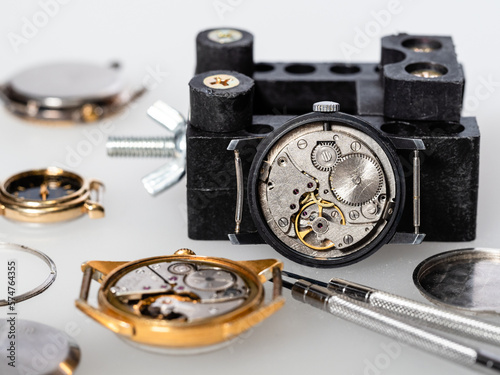 old open mechanical watches and screwdriver closeup on white board in watchmaker workshop