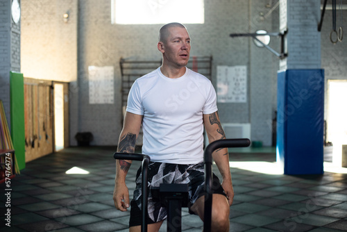Athletic man training on assault bike in crossfit gym.