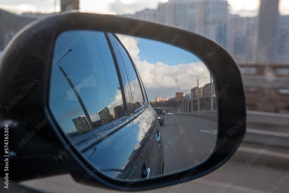 Reflection in the side mirror of a car when driving around the city.