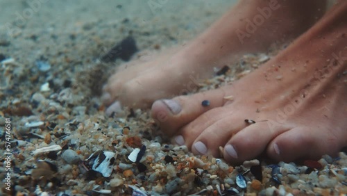 Feet, sea and shells with the barefoot woman in the ocean standing with toes in the current, tide and flow. Water, nature and freedom with a female on holiday, vacation or getaway by the beach photo