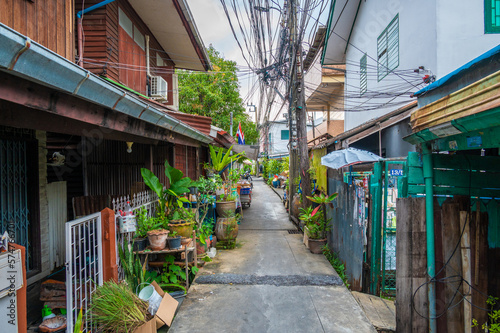 Narrow city street at Bangkok city, Thailand. Small street with houses and green plants around. © Martin