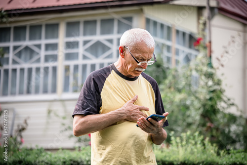 An elderly man relaxes a tense nerve in the chest area by pressing. Treatment remotely by phone. Online therapist. Teletherapy