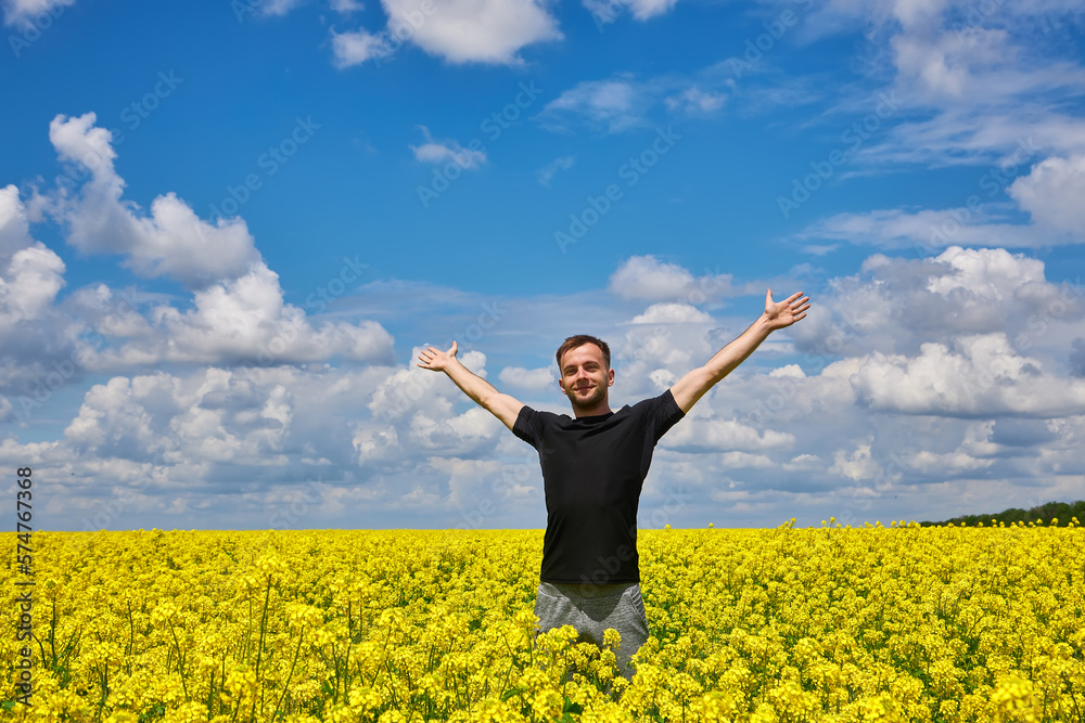 Man stands in a yellow field rejoicing raises his hands to the sky. Man stands in a yellow field rejoicing raises his hands to the sky.