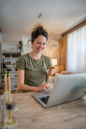 happy woman online shopping use credit card laptop computer at home
