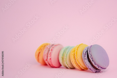 Low angle close up view of an assortment of colorful French macarons on pink background with selective focus