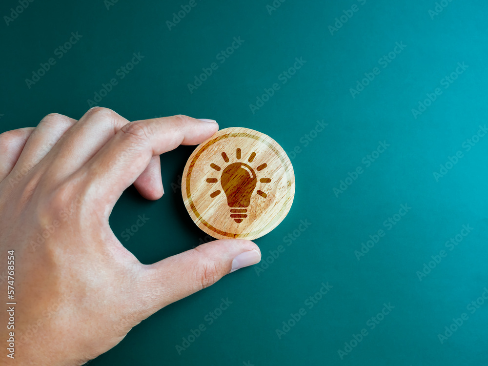 Green ecology, Inspiration and creative system management and environment development for sustainable concepts. Creative idea light bulb icon on round wooden block in hand on blue green background. Green ecology, Inspiration and creative system management and environment development for sustainable concepts. Creative idea light bulb icon on round wooden block in hand on blue green background.