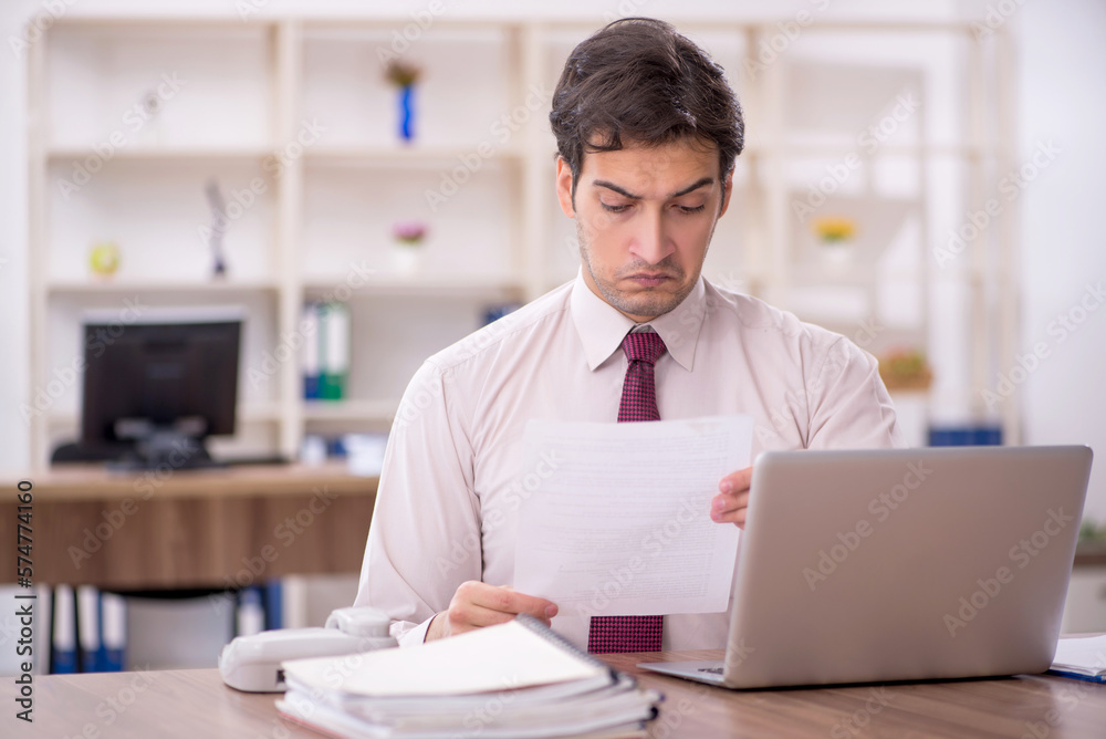 Young male employee and too much work in the office Young male employee and too much work in the office