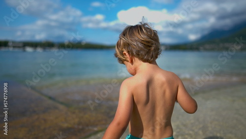 One small boy walks at beach shore during summer vacations. Child walking outdoors shirtless enjoying nature. Happiness concept © Marco