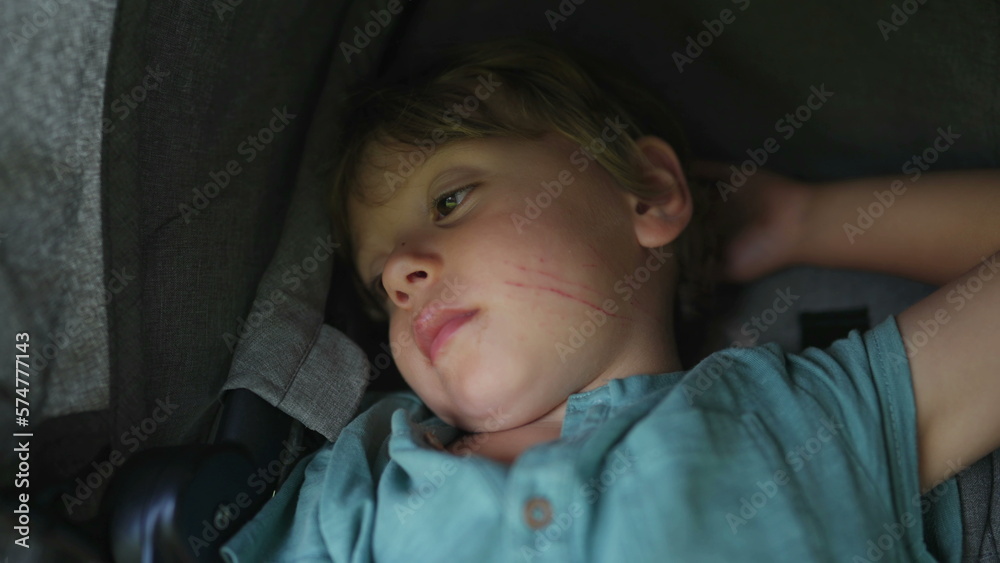 One small boy sitting inside stroller waking up from nap One small boy sitting inside stroller waking up from nap