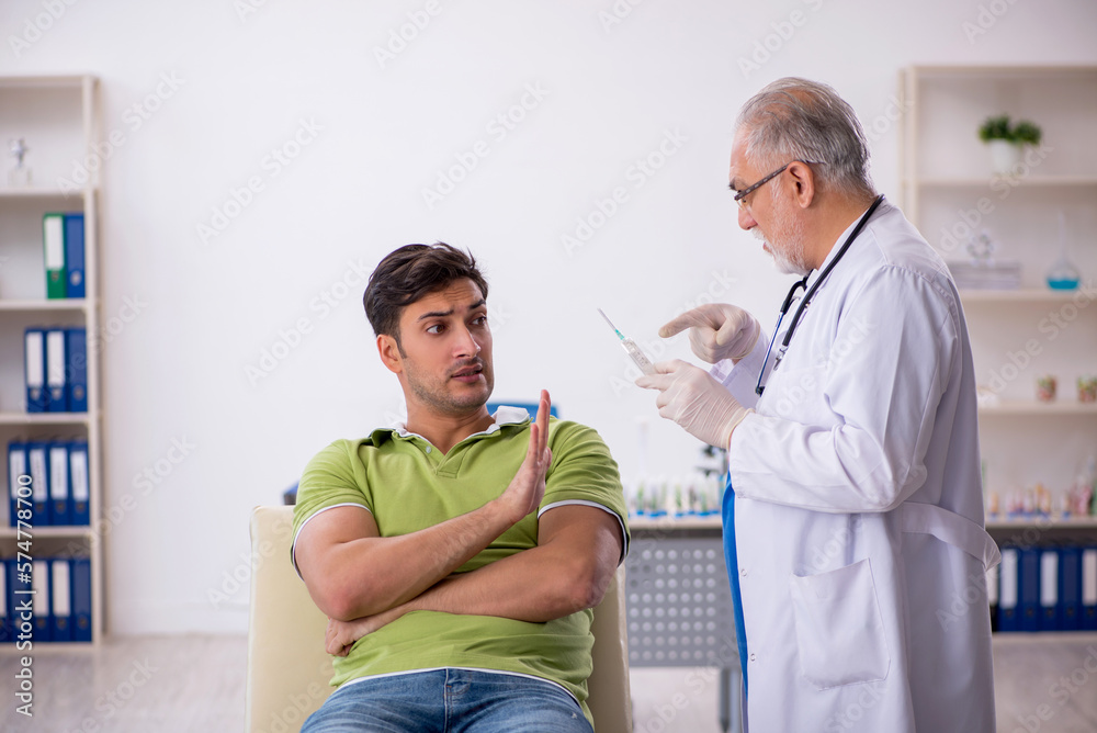 Obraz premium Young male patient visiting old male doctor in vaccination conce