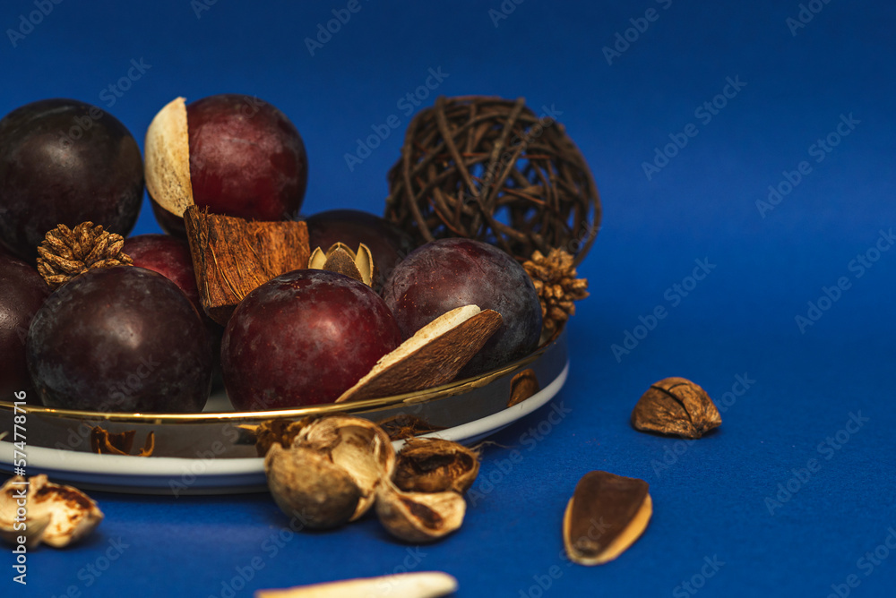 Obraz premium Juicy plums on a gold-rimmed platter. On a blue background. 