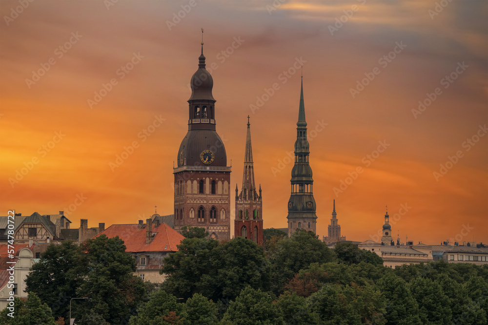View of the church towers of the old town of Riga. Orange sky at sunset