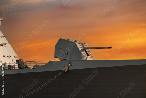 Large cannon on board an army warship, orange sky background. A gun turret on a battleship