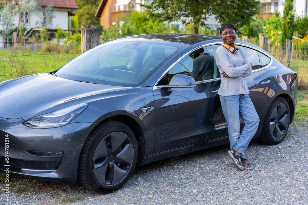 Side view of happy African woman standing in front of her car. Side view of happy African woman standing in front of her car.