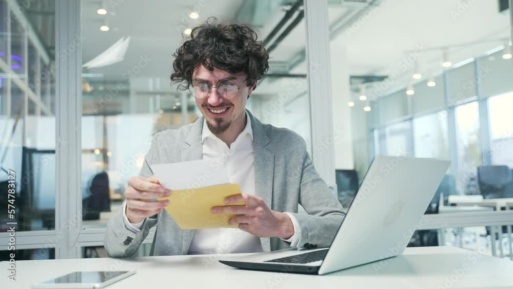 Happy business man freelancer received open envelope mail letter with great news with project work investment success or salary increase Excited entrepreneur celebrating victory at workplace indoors Happy business man freelancer received open envelope mail letter with great news with project work investment success or salary increase Excited entrepreneur celebrating victory at workplace indoors