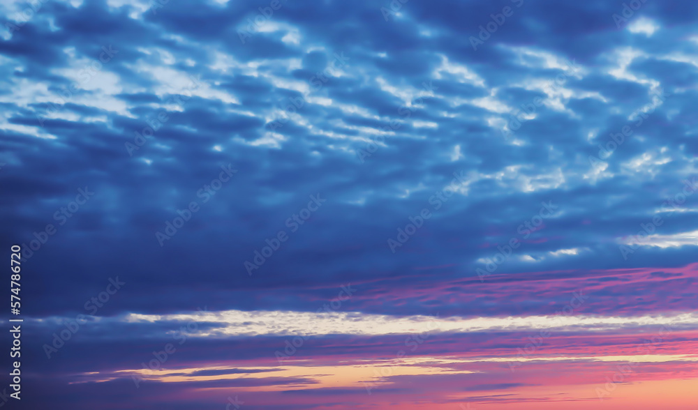Natural sunset background, dark blue clouds and light pink clouds backlit by the setting sun