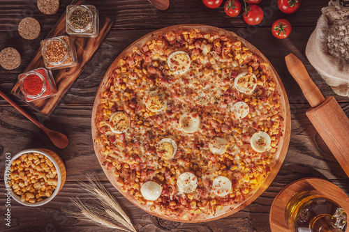 Pizza with mozzarella, bacon, corn, boiled eggs and oregano - Top view.