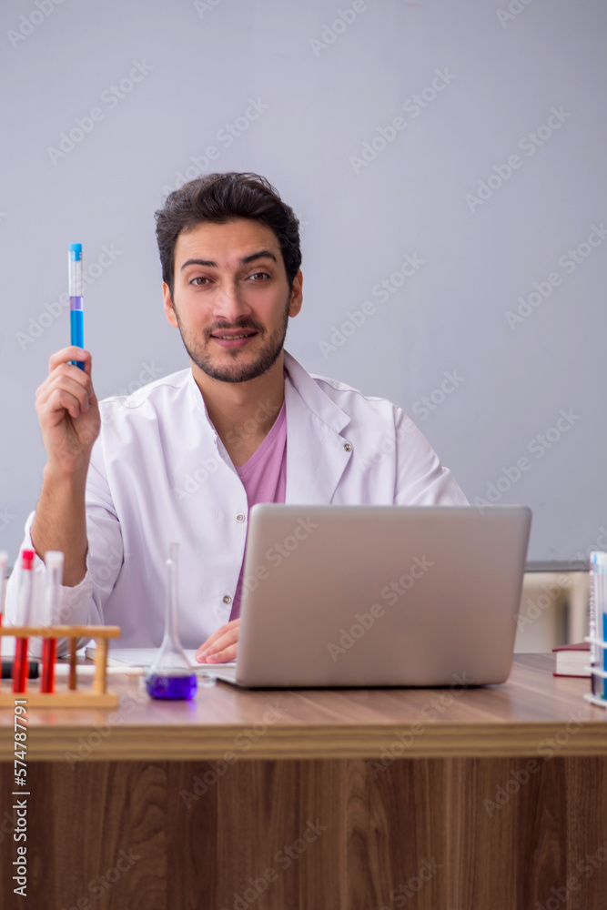 Young male chemistry teacher sitting in the classroom Young male chemistry teacher sitting in the classroom