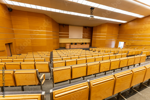 Interior of big conference hall full of gray folding chairs and wooden walls